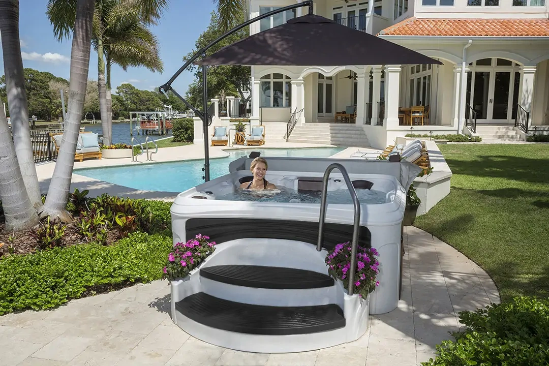 Owner relaxing in a DreamMaker spa beside a luxury waterfront pool - rated #1 in product value